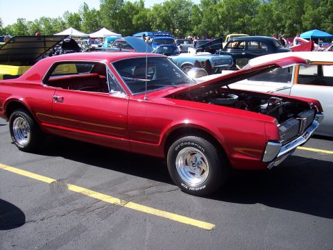 1972 Ford Ranchero - A red 1967 Mercury Cougar is displayed at a car show with its hood up.