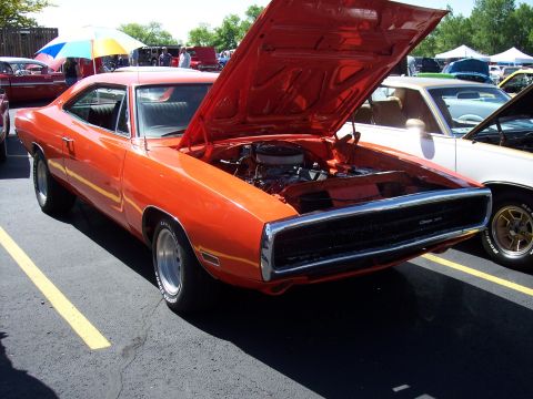 1972 Ford Ranchero - An orange 1970 Dodge Charger is displayed with its hood open at a car show.