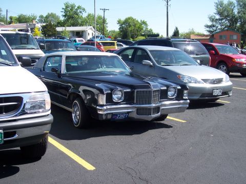 1972 Ford Ranchero - A black coupe with a white vinyl roof is parked in a lot next to other vehicles.