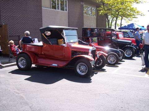 1972 Ford Ranchero - A line of classic cars, including a red vintage pickup truck, are parked outside a brick building.