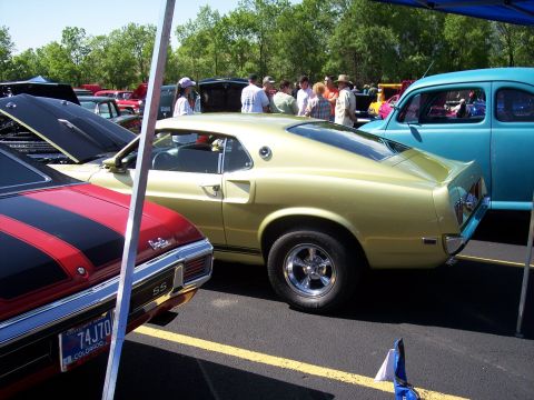 1972 Ford Ranchero - A gold 1969 Ford Mustang coupe is parked next to other classic cars at an outdoor event.