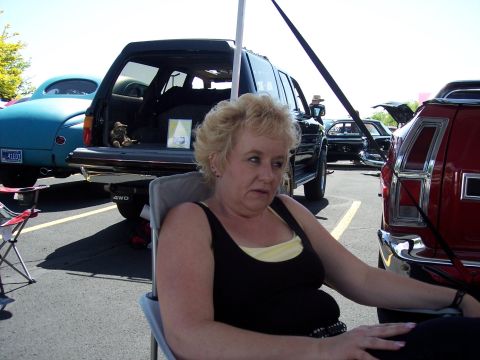 1972 Ford Ranchero - A woman sits in a chair at an outdoor event with several vehicles visible behind her.