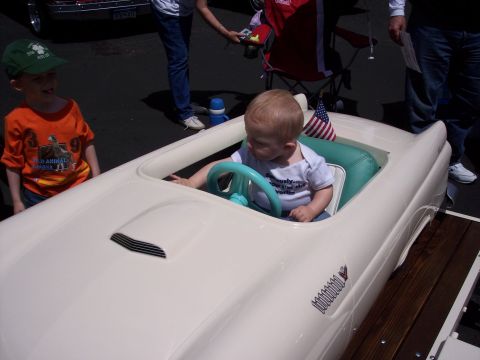 1972 Ford Ranchero - Baby is playing in a toy car at an outdoor event.