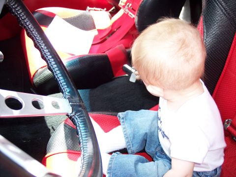 1972 Ford Ranchero - A child sits in a car's interior, facing away from the camera, with a view of the steering wheel and racing seats.