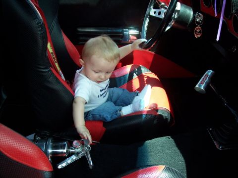1972 Ford Ranchero - A baby sits in a car's interior, exploring the steering wheel and keys.