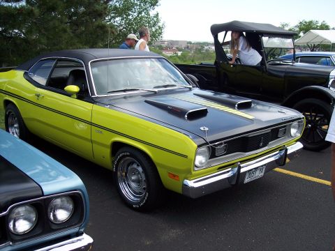 1972 Ford Ranchero - A bright green 1973 Plymouth Duster is parked at an outdoor car show with other vehicles visible.