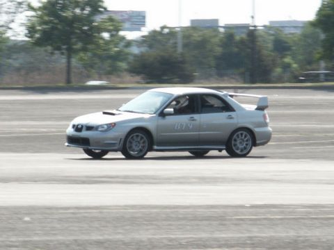 2001 Mercury Grand Marquis - A silver sedan with a prominent rear spoiler is captured in motion on a paved surface.