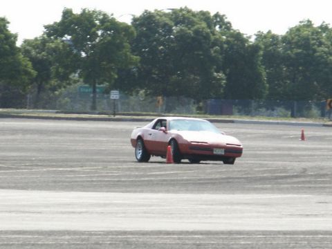 2001 Mercury Grand Marquis - A red sports car navigates a course marked by orange cones on a paved surface.