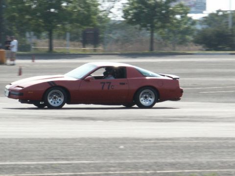 2001 Mercury Grand Marquis - A red Pontiac Firebird is captured in motion on a paved surface, possibly during a track event.
