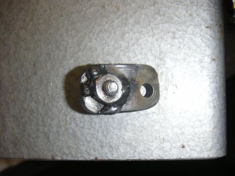 1996 Ford Crown Victoria - A close-up view of a metal bracket with a bolt and weld, placed on a textured surface.
