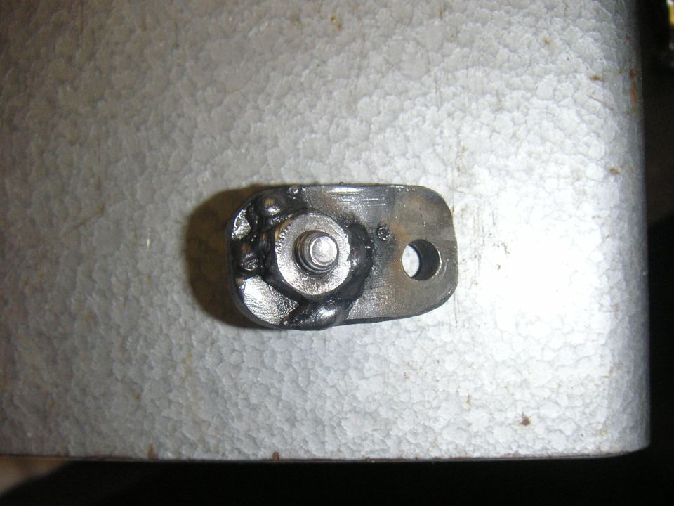 Metal bracket with a bolt and weld, on a textured surface