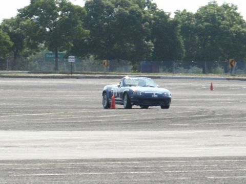 2001 Mercury Grand Marquis - A blue convertible sports car is seen on a track, maneuvering around orange cones during an event.