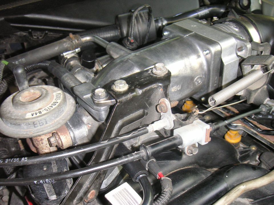 Engine components with hoses, cables, and a silver throttle body