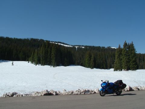 2007 Kawasaki Ninja - A blue motorcycle is parked on the side of a road with snow and trees in the background.