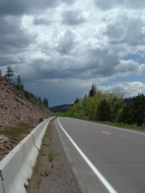 2007 Kawasaki Ninja - A scenic highway curves through a mountainous landscape under a dramatic, cloudy sky.
