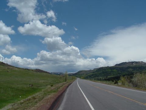 2007 Kawasaki Ninja - A two-lane highway winds through a scenic landscape under a sky filled with fluffy white clouds.