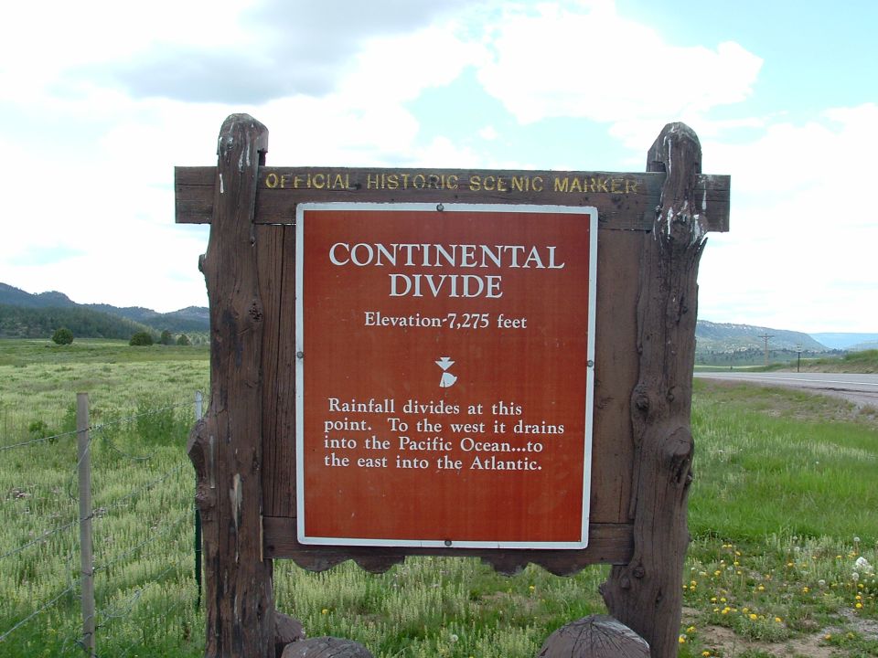 Official historic scenic marker for the Continental Divide, showing elevation 7,275 feet and explaining how rainfall divides here to flow to the Pacific or Atlantic oceans