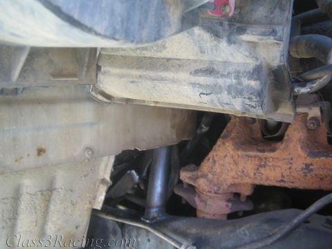 1990 Ford Bronco - Undercarriage of a vehicle showing a metal pan, exhaust pipe and a rust-colored differential housing.