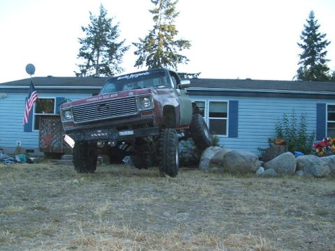 1976 GMC Sierra 2500 - A heavily modified pickup truck is shown with its front wheels elevated on large rocks.