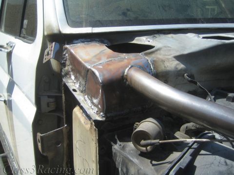 1990 Ford Bronco - freshly welded curved metal panel joins a tubular bar inside the partially stripped body shell of a white vehicle.