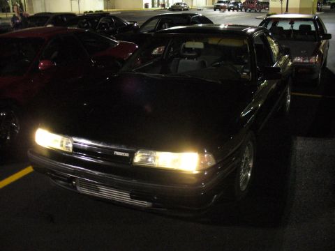 1991 Ford Probe - A 1991 Mazda 626 is parked in a lot at night, with its headlights on.