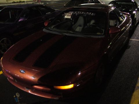 1991 Ford Probe - Front view of a red 1991 Ford Probe with racing stripes, parked at night.