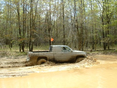1991 Ford Bronco - Pickup truck navigating a challenging muddy off-road course.