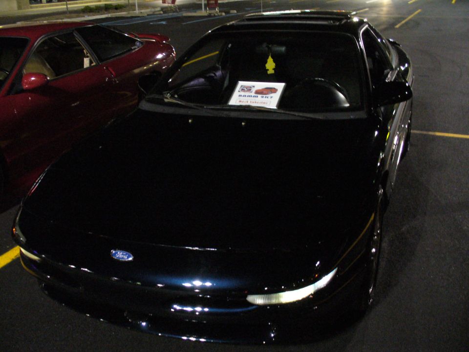 Dark blue coupe with a sunroof, parked next to a red car. A sign is on the dashboard