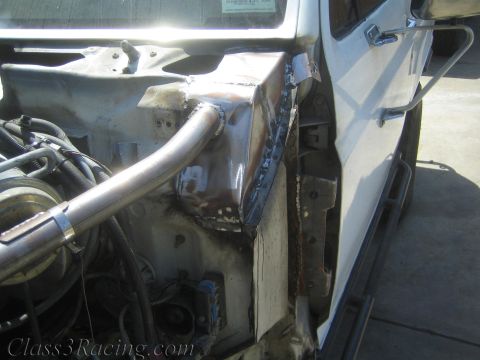 1990 Ford Bronco - Close-up of a white truck's lower cab and rocker panel showing a raw welded sheet-metal repair patch and a tubular chassis bar.