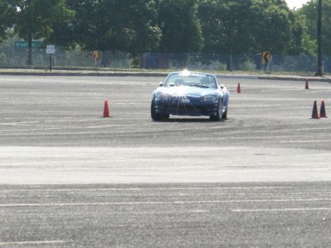 2001 Mercury Grand Marquis - A blue convertible sports car is seen maneuvering through a cone course on a paved track.