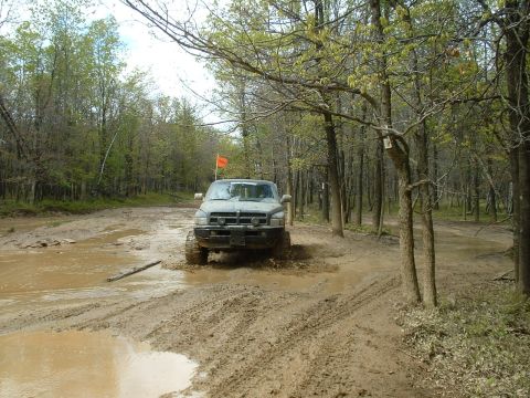 1991 Ford Bronco - Truck navigating a muddy trail in a wooded area.