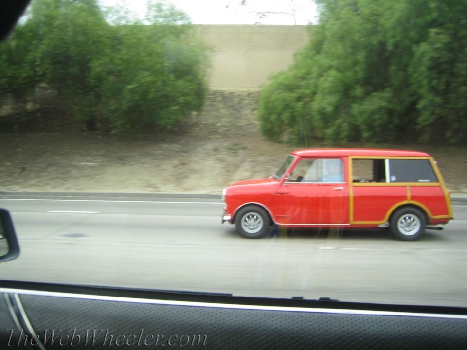 Red classic Mini estate with wood-look side trim driving on a highway