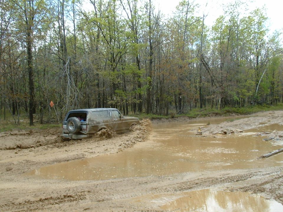 Brown 1991 Ford Bronco stuck in mud, rear view