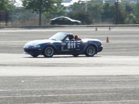 2001 Mercury Grand Marquis - A blue convertible sports car with racing number 811 navigates a track, with another car in the background.