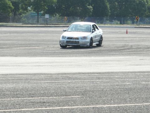 2001 Mercury Grand Marquis - A white Subaru Impreza WRX sedan navigates a course marked by cones on a paved lot.