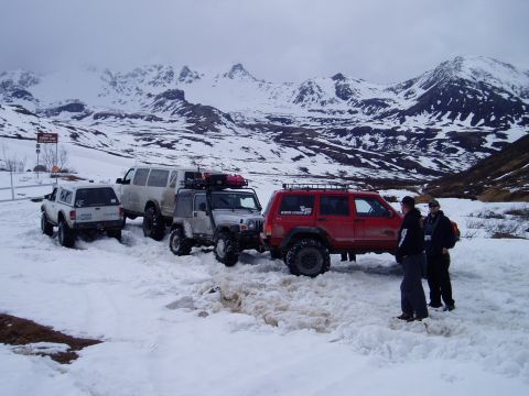 2000 Ford E350 - A group of off-road vehicles are stopped in a snowy landscape with mountains visible.