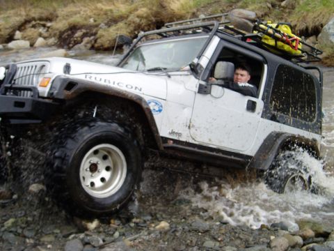 2000 Ford E350 - This Jeep Wrangler Rubicon is navigating a rocky stream, demonstrating its off-road capabilities.