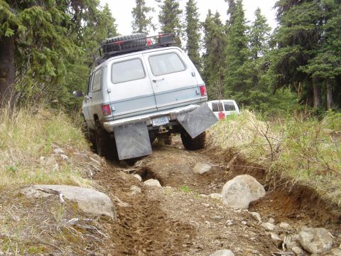 2000 Ford E350 - A silver van navigates a challenging off-road trail with another van visible in the background.