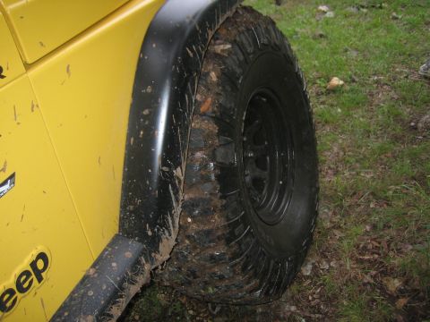 2001 Jeep Wrangler - A yellow Jeep Wrangler is shown from the side, with its tire covered in mud.