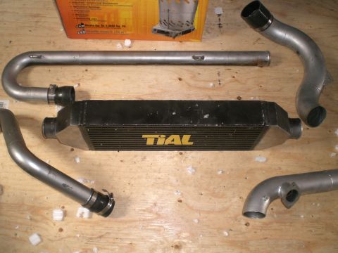 1995 Ford Probe - A TIAL intercooler and several pieces of piping are laid out on a wooden surface.