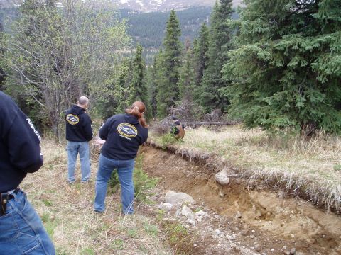 2000 Ford E350 - A group of people observe a steep, dug-out path in a forested mountain landscape.
