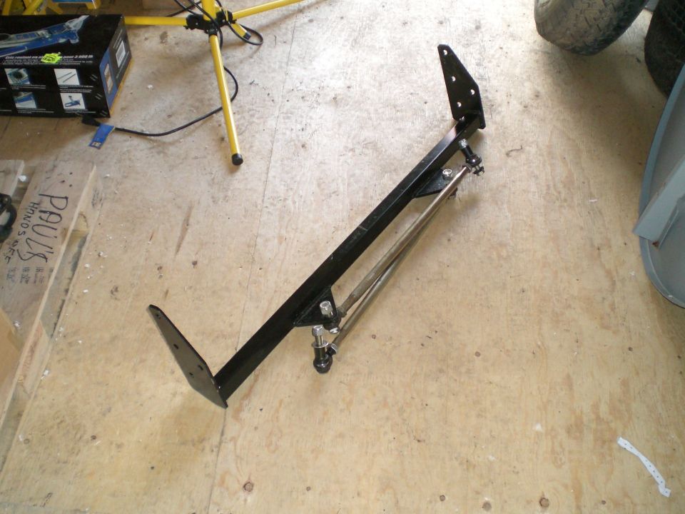 Black painted steel mounting bracket with adjustable link rod on plywood floor