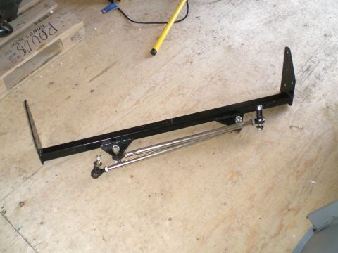 1995 Ford Probe - Black powder-coated square-tube suspension crossmember with drilled bolt-on mounting plates at each end, fitted with two adjustable heim-jo…