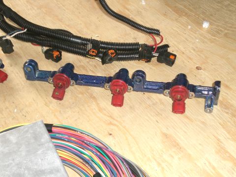 1995 Ford Probe - Close-up of a modified fuel rail with injectors and associated wiring harness, likely for an engine upgrade.