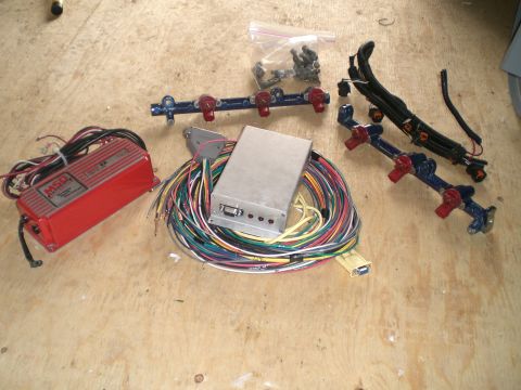 1995 Ford Probe - Engine parts laid out on a wooden surface, including an MSD ignition box, a custom ECU, and a fuel rail with injectors.