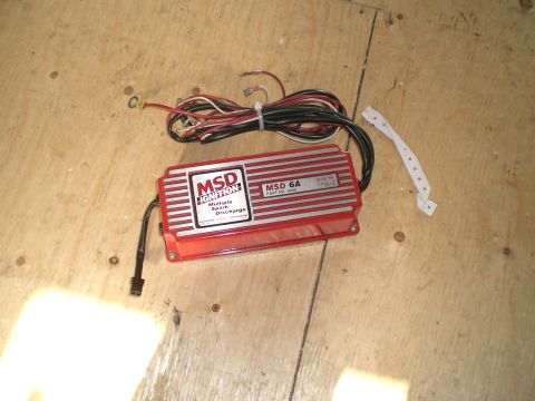 1995 Ford Probe - Red MSD 6A multiple spark discharge ignition box, part no. 6200, serial 179645, lying on a plywood floor with its coiled wiring harness and…