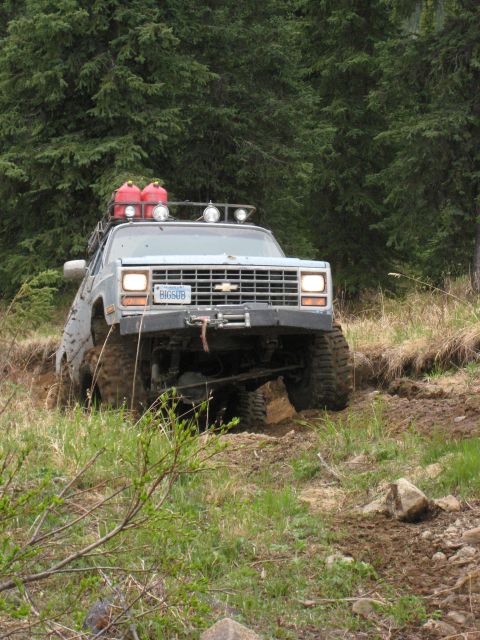 2000 Ford E350 - This modified pickup truck is navigating a challenging off-road trail, with its tires deep in mud.