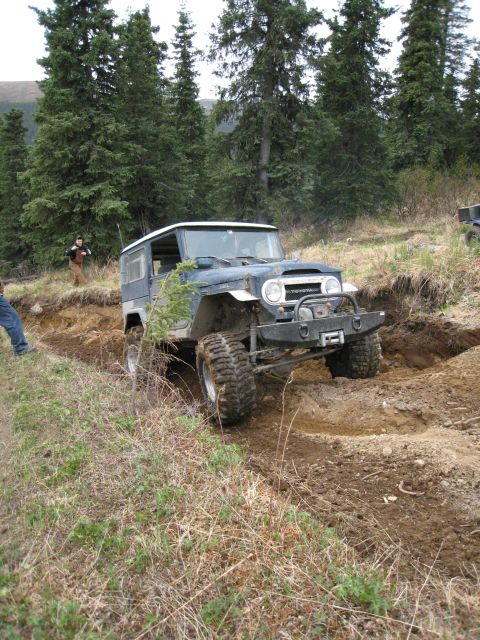 2000 Ford E350 - A Toyota Land Cruiser FJ40 navigates a challenging off-road trail with a winch and large tires.