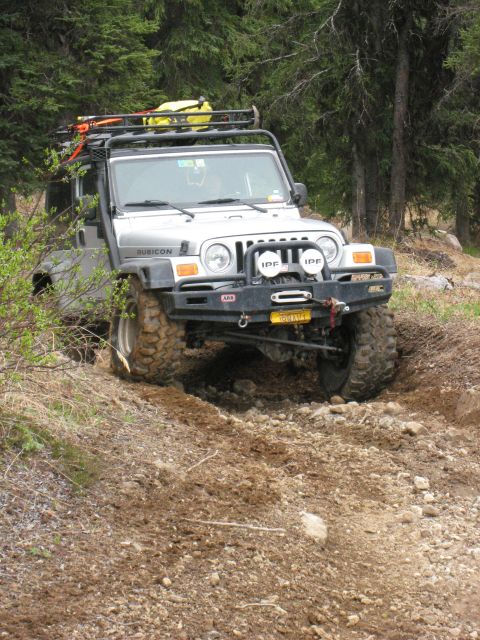 2000 Ford E350 - This modified Jeep Wrangler Rubicon is equipped for off-road adventures, a roof rack and tires as it tackles a challenging dirt path.