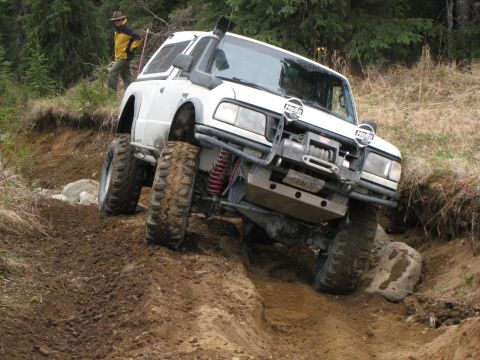 2000 Ford E350 - Modified SUV tackling a challenging off-road trail with a person observing from the side.